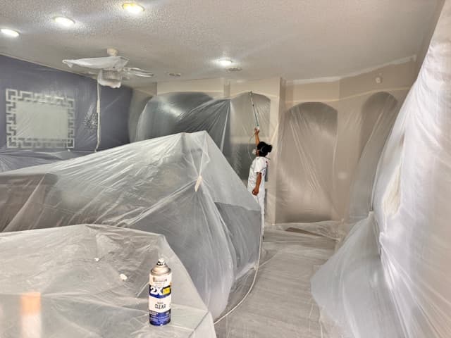Painter applying a fresh coat in a fully protected living space during interior repainting