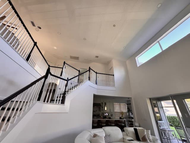 Double-height stair hall repaint with bright walls, dark rails, and a crisp modern contrast