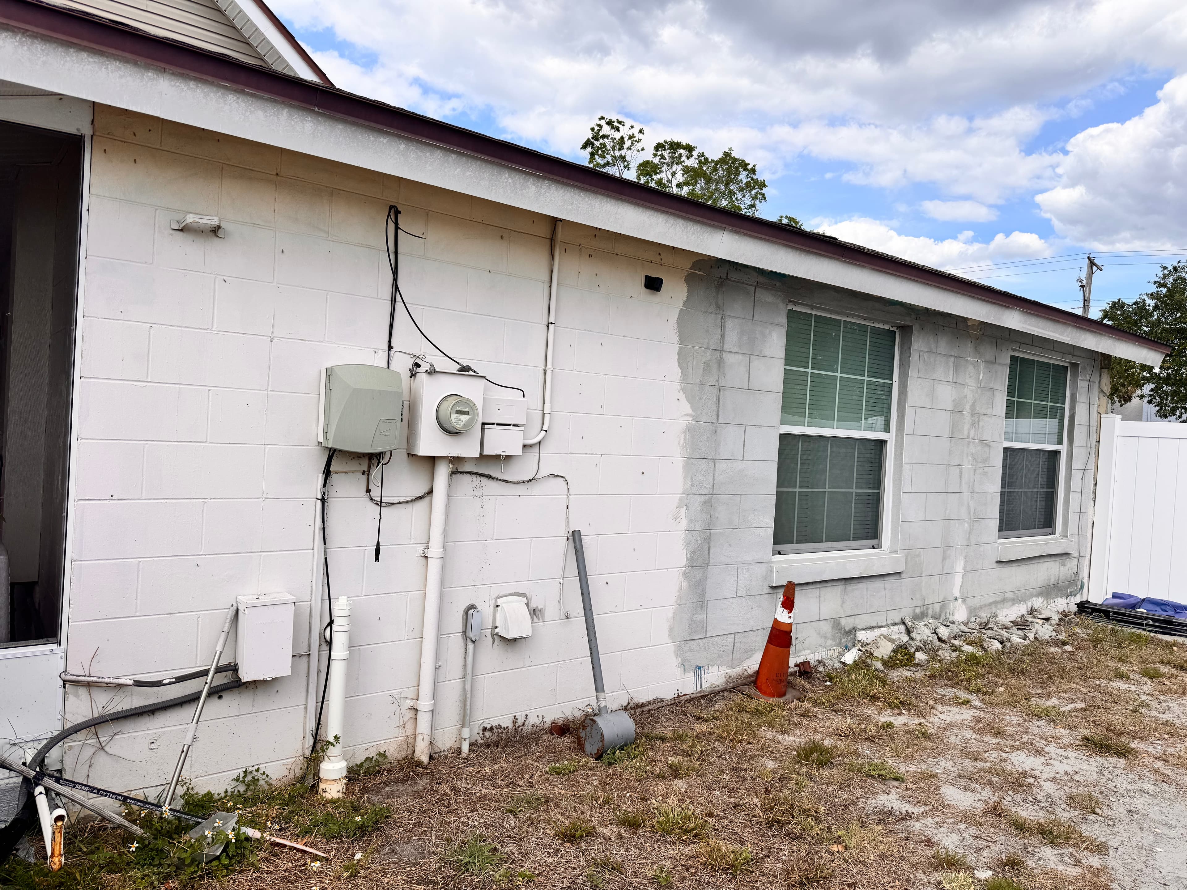 Before photo of residential home exterior front view with original beige paint and worn surfaces