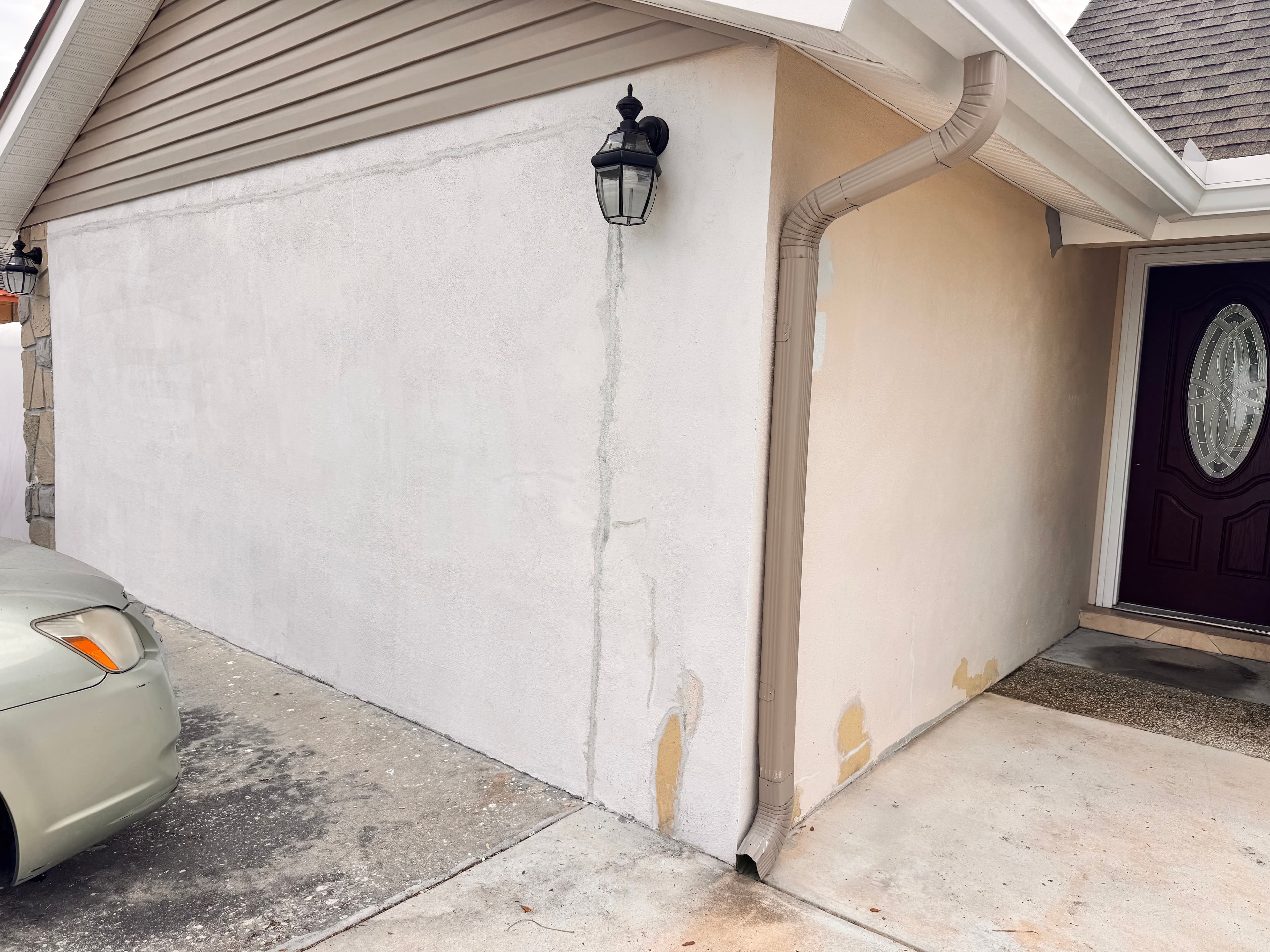 Before photo of residential home exterior with original paint and driveway view