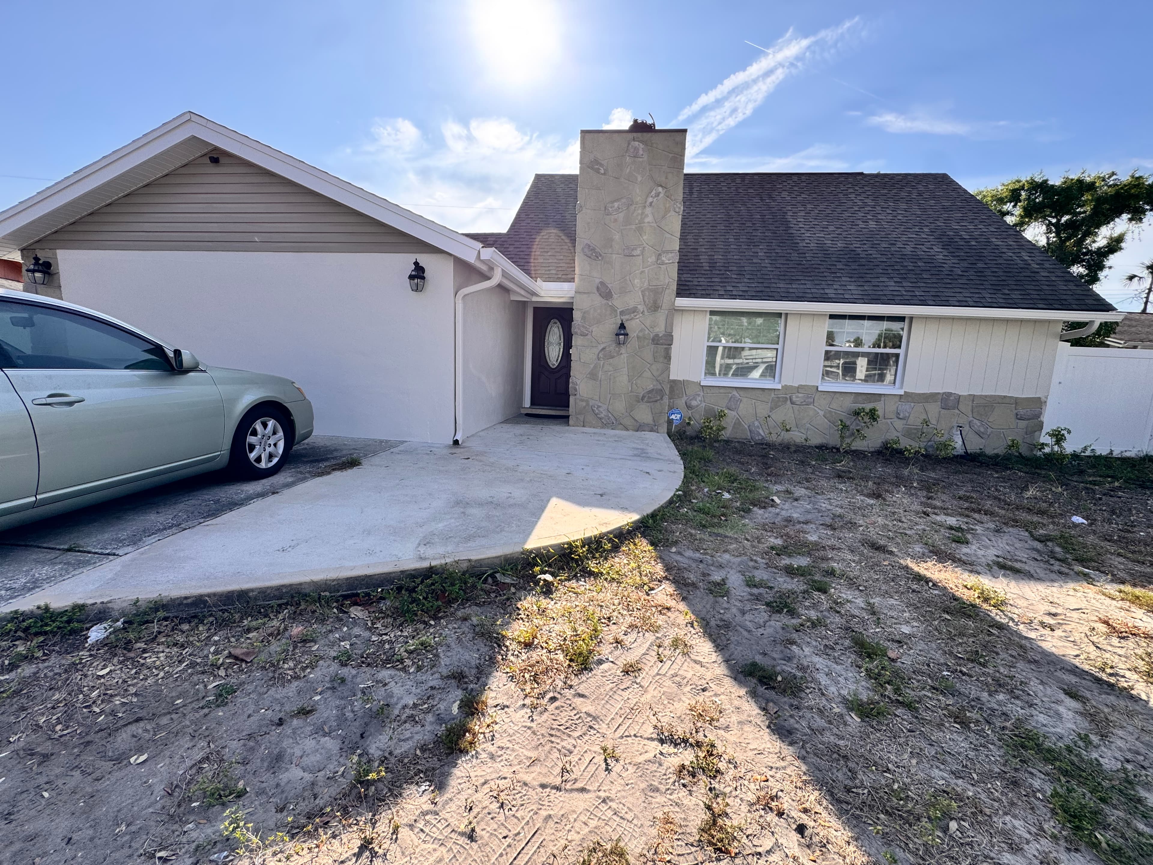 After photo of residential home front view with bright white siding, dark trim, and refreshed landscaping